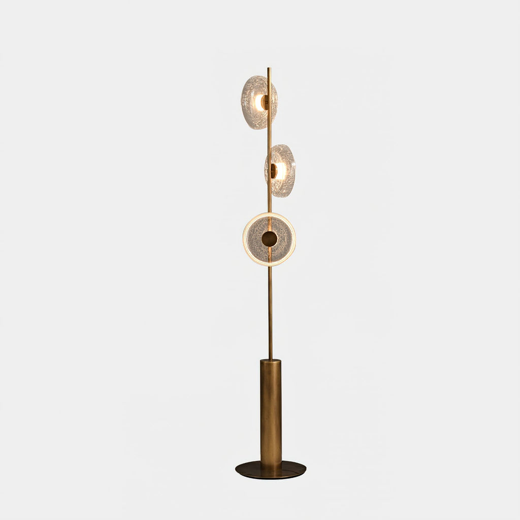Clérachic floor lamp on a pale grey backdrop, its three glass discs lit and the lowest showing a bright ring of light.