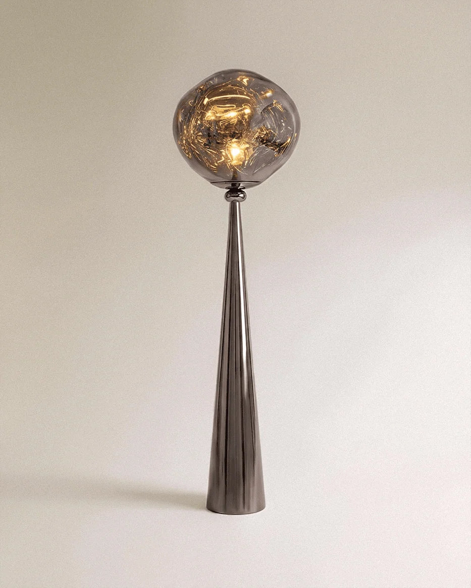 Clérachic floor lamp with a dark gunmetal cone stem and a rippled grey glass-look shade lit warm on a plain backdrop.