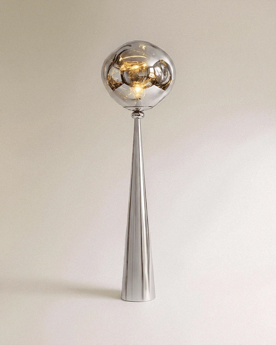 Clérachic floor lamp with a mirror-bright chrome cone stem and a rippled silver-grey shade glowing warm.