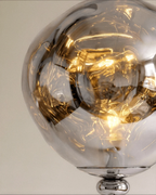 Clérachic close-up of the rippled chrome-toned shade lit warm, resting on a polished chrome collar and ball joint.