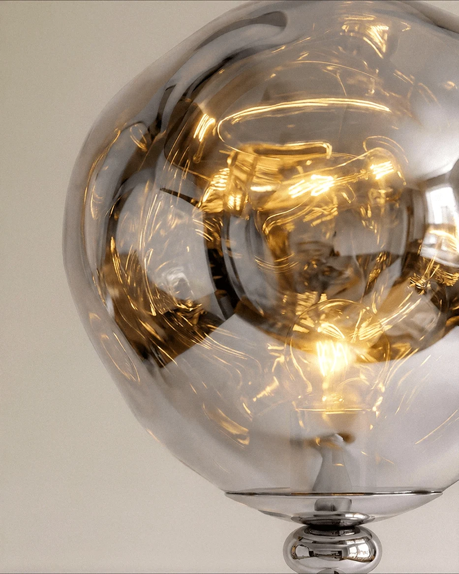 Clérachic close-up of the rippled chrome-toned shade lit warm, resting on a polished chrome collar and ball joint.