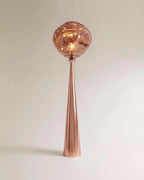 Clérachic floor lamp with a polished rose gold cone stem and a rippled blush shade glowing warm.