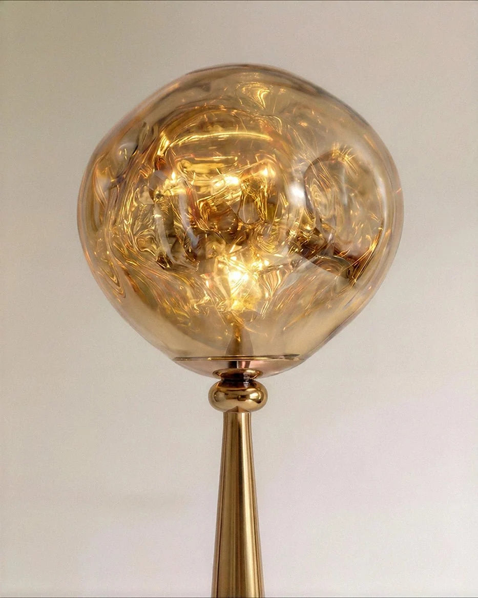 Clérachic close-up of the rippled amber-gold shade glowing warm above a polished gold ball joint and cone neck.