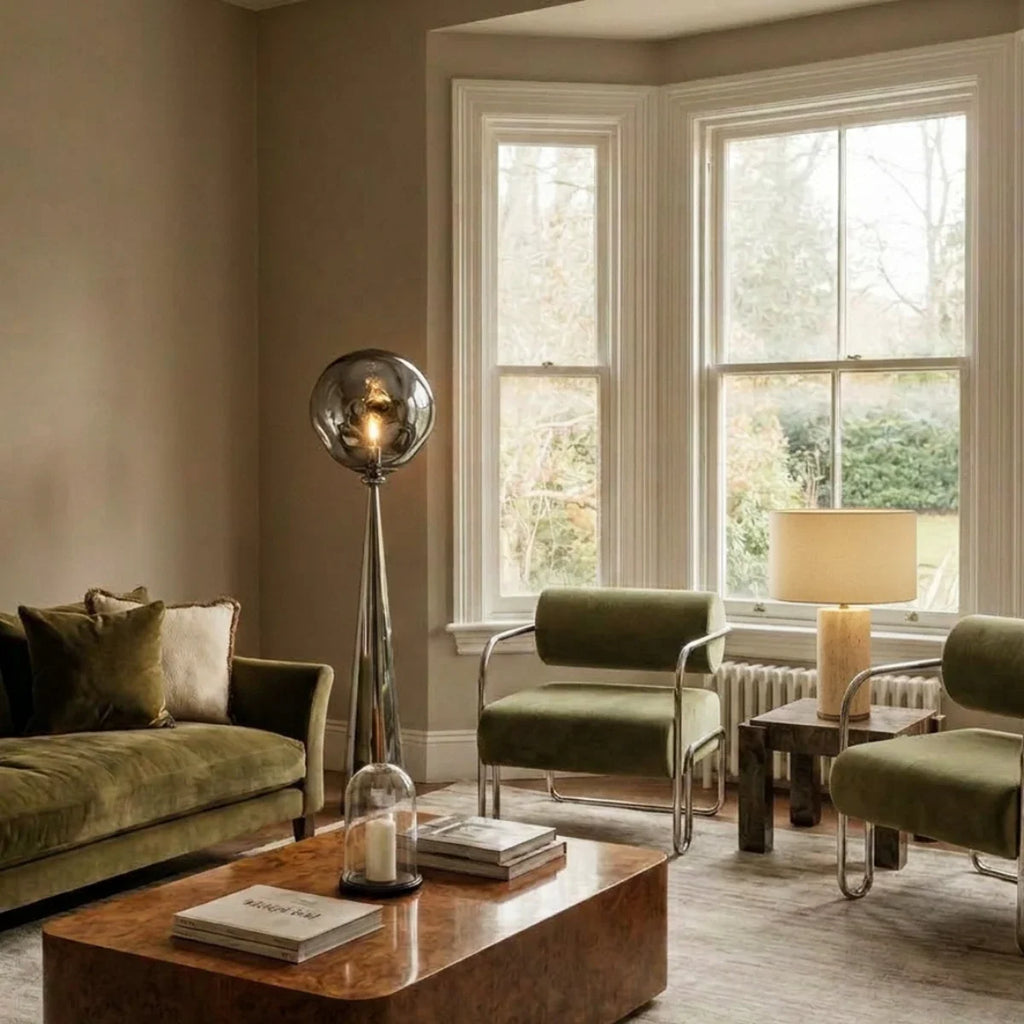 Clérachic chrome floor lamp with a rippled grey shade in a living room with olive velvet seating and a burr wood table.