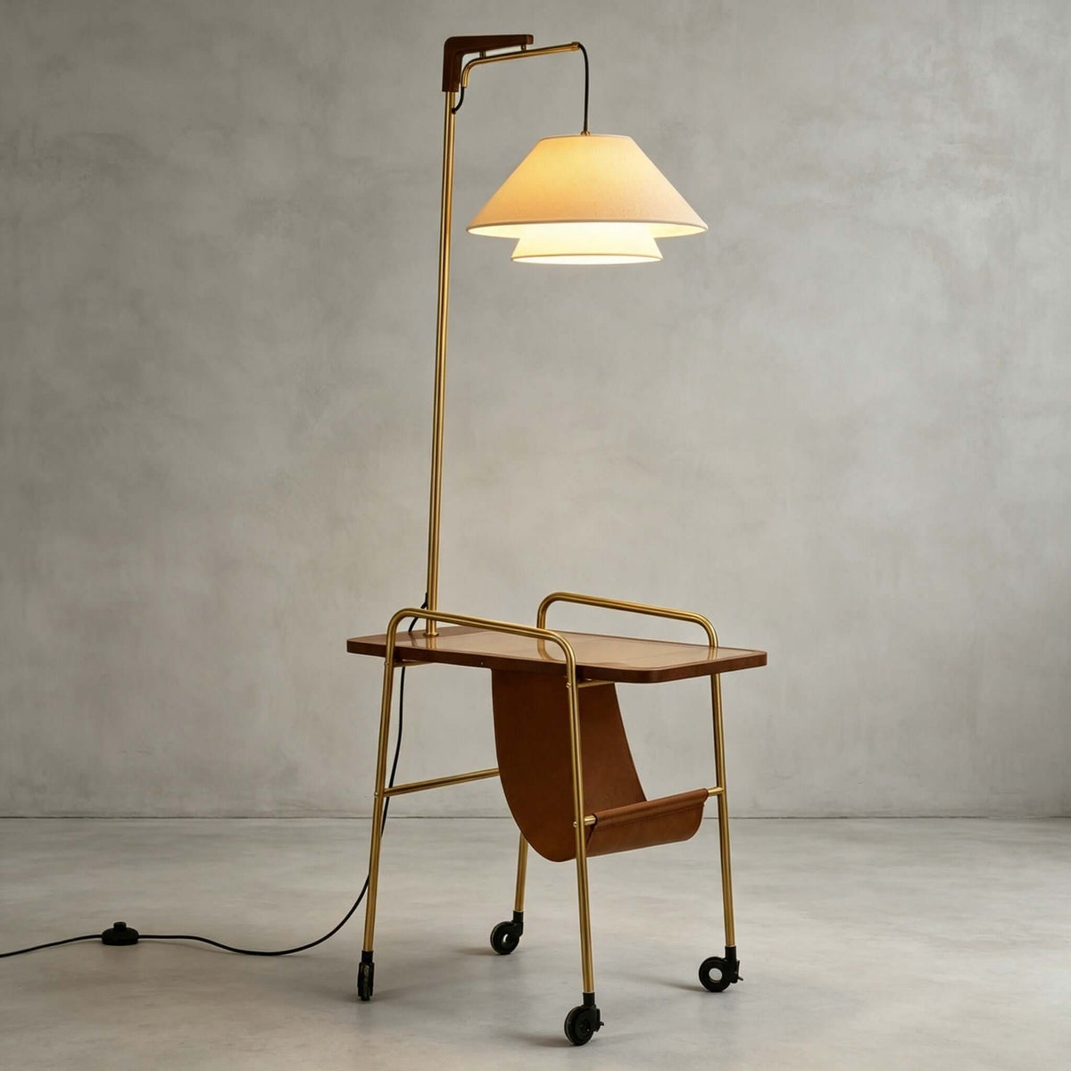 Clérachic floor lamp with a brass stem, a brown tabletop and a tan leather sling, with its cord trailing on the floor beside it.