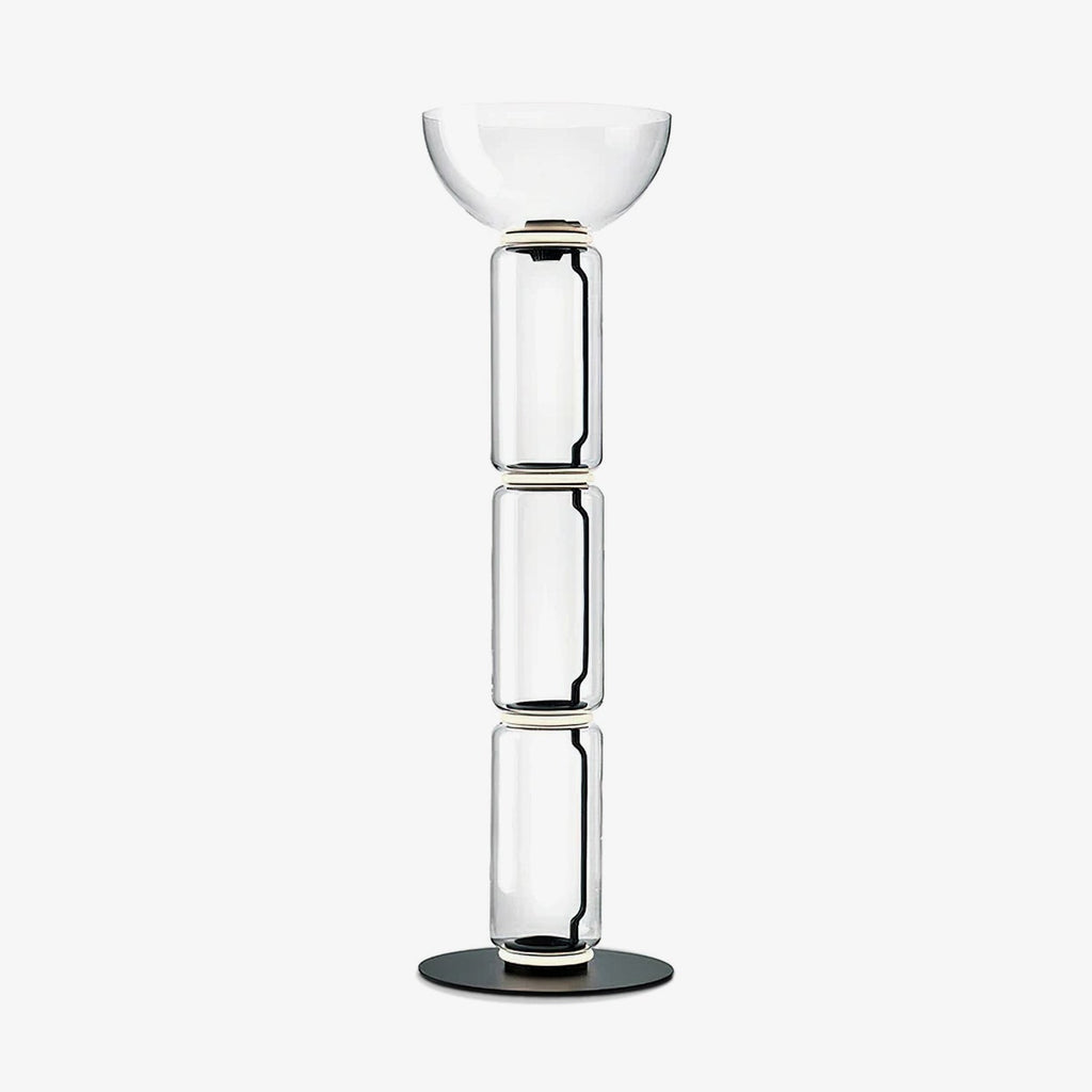 Clérachic modular glass floor lamp on a plain white backdrop, three clear glass cylinders under a wide bowl shade on a round black base.