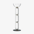 Clérachic modular glass floor lamp on a plain white backdrop, three clear glass cylinders under a wide bowl shade on a round black base.