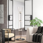 A Clérachic glass floor lamp with a cone shade between steel-framed glass doors, with a cane-backed armchair and a plant nearby.