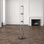 Tall unlit Clérachic glass floor lamp on a herringbone floor in a white panelled room, black connectors showing between the glass sections.