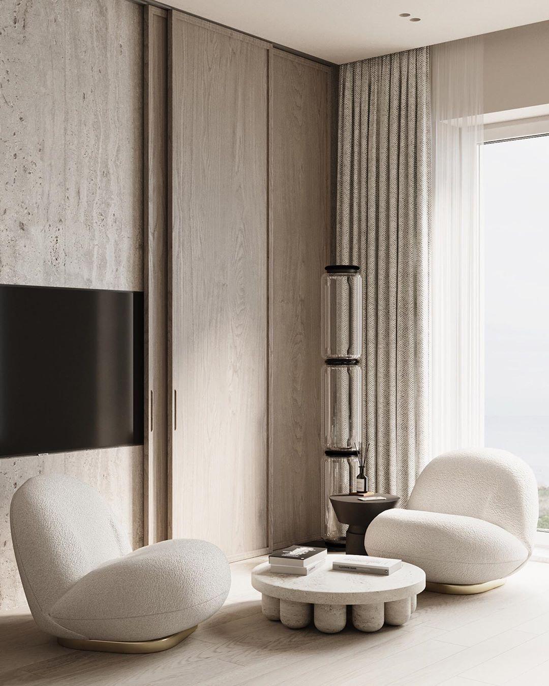 Slim Clérachic glass floor lamp in a pale living room, beside a sheer curtain, a wall-mounted screen and two cream lounge chairs.