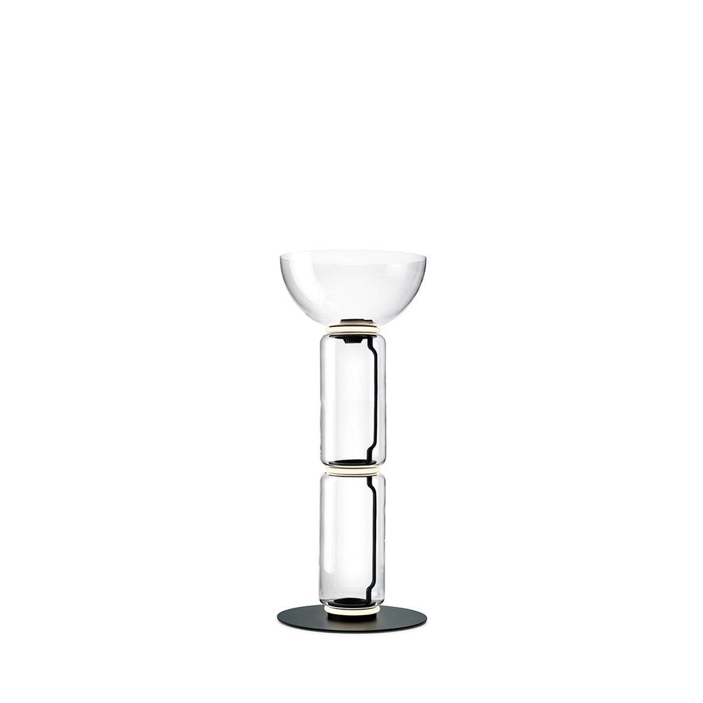 Clérachic glass floor lamp with a bowl shade over two clear cylinders on a round black base, against a plain white backdrop.