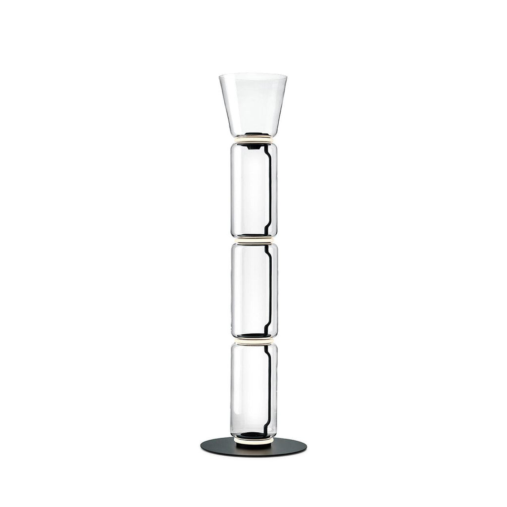 Clérachic glass floor lamp with a small cone shade over three clear cylinders, on a round black base against white.