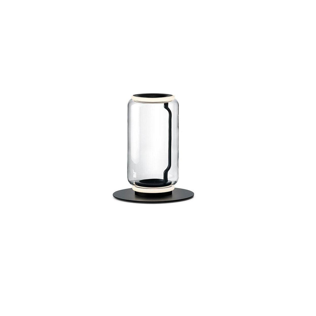 Clérachic table-height glass lamp with one clear cylinder and a lit ring at the top, on a round black base against white.