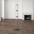 Unlit Clérachic glass floor lamp in a large white panelled room, a herringbone floor and a stone fireplace behind it.