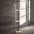 Clérachic glass floor lamp with a cone shade lit in a room with crumbling walls and strong sun, over a stone floor.