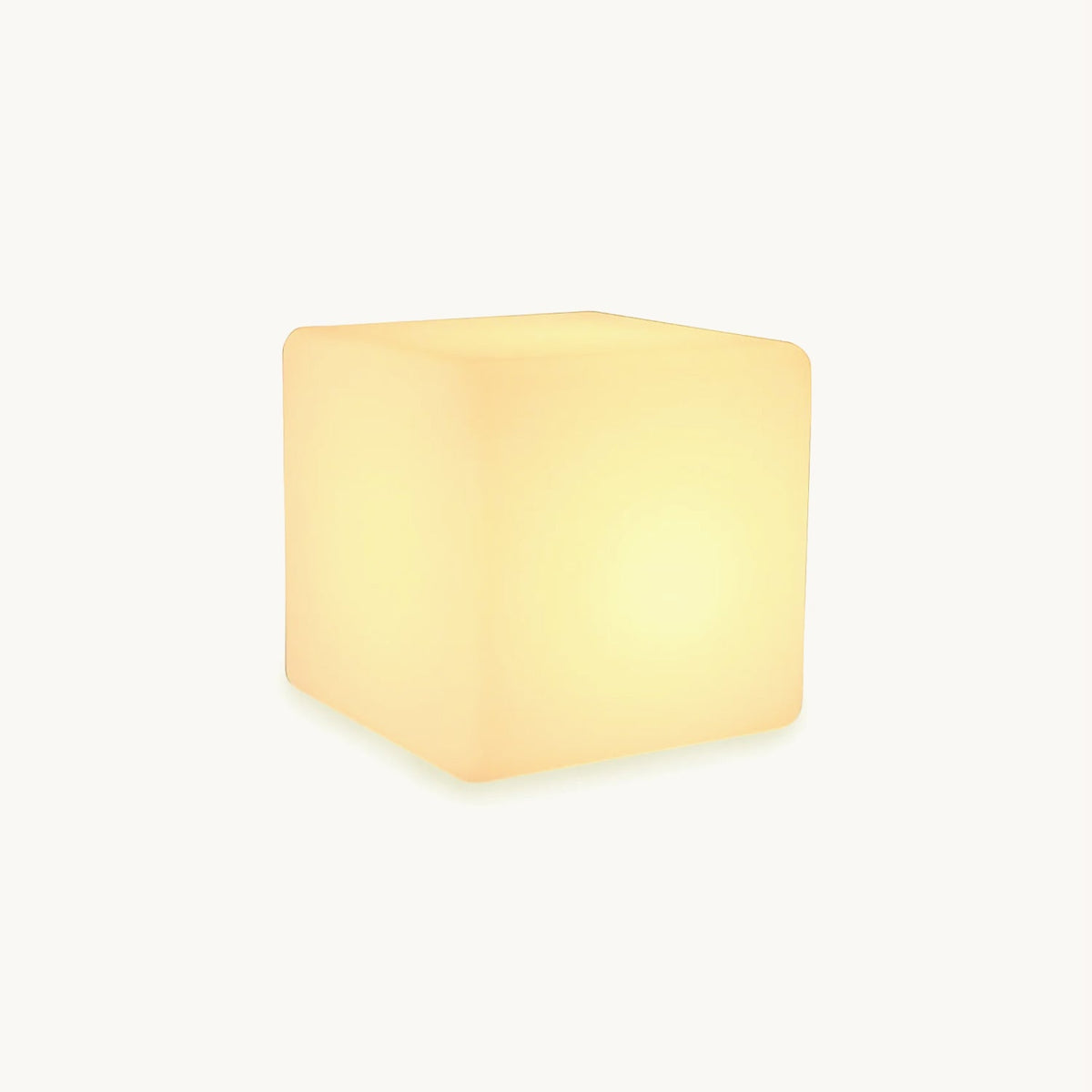 A glowing white cube-shaped Clérachic floor lamp with softly rounded corners, lit warm, on a plain white backdrop.