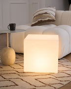 Beside a bouclé sofa, a patterned cushion and a black mug, this white Clérachic cube lamp glows on a zigzag rug.
