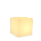 Seen from a slightly higher angle on a white backdrop, this white Clérachic cube lamp glows with a soft warm light.