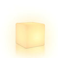 With a soft halo of warm light around it, this white Clérachic cube lamp stands on a white backdrop.