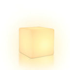 With a soft halo of warm light around it, this white Clérachic cube lamp stands on a white backdrop.