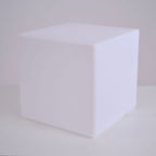 A white Clérachic cube lamp, unlit, with softly rounded edges, on a pale surface against a grey wall.