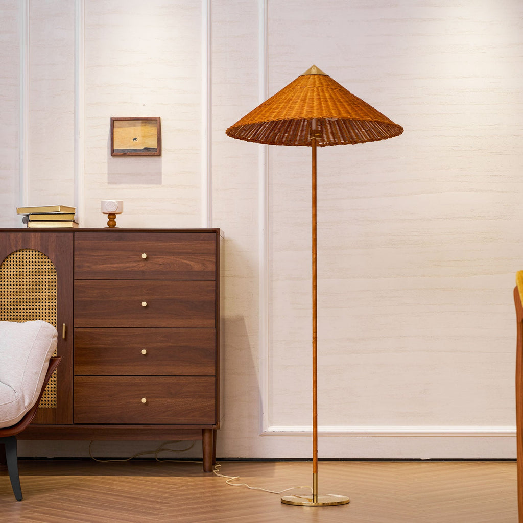 Closer view of this Clérachic floor lamp with a rattan shade, in front of a walnut chest with brass knobs and a small framed picture.