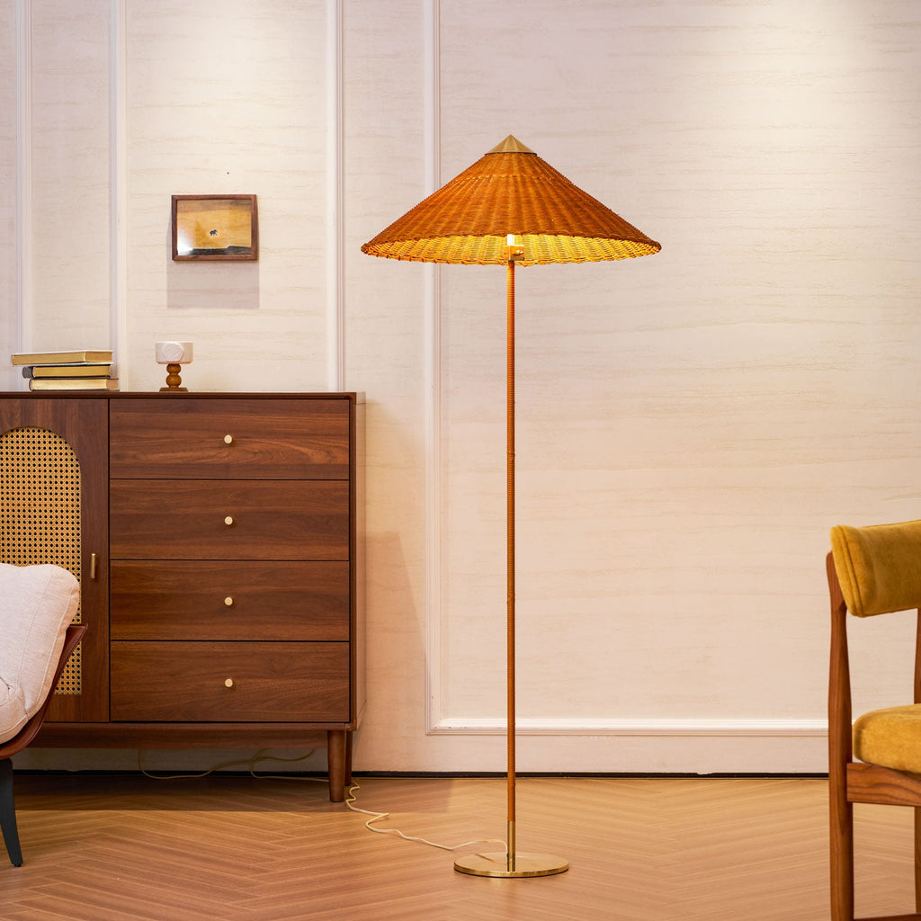 Full-length view of this Clérachic floor lamp with a rattan shade, in front of a walnut chest of drawers and a framed picture.