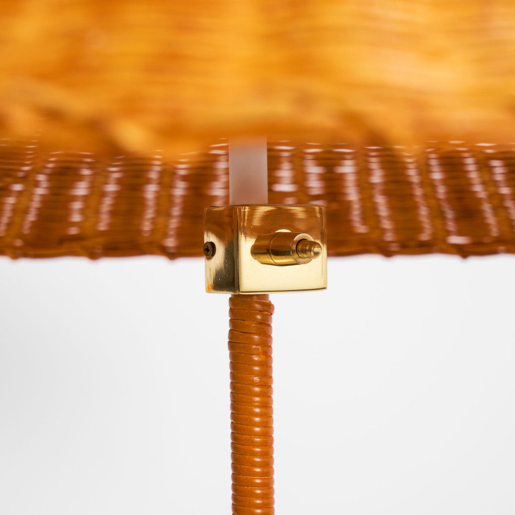 Close view of the brass fitting and the cane-wrapped stem beneath the woven shade on this Clérachic floor lamp.