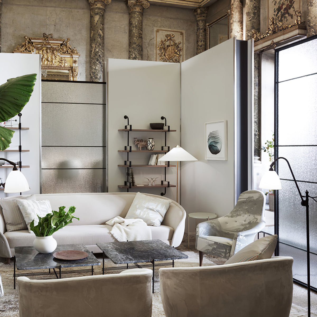 This Clérachic floor lamp with a white shade stands in a bright room with an arched glass door, behind a cream sofa and two armchairs.