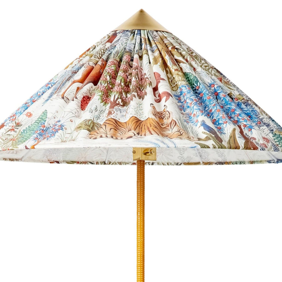 Close view of the pleated printed shade on this Clérachic floor lamp, with a brass cap, a tiger and a cane-wrapped stem.