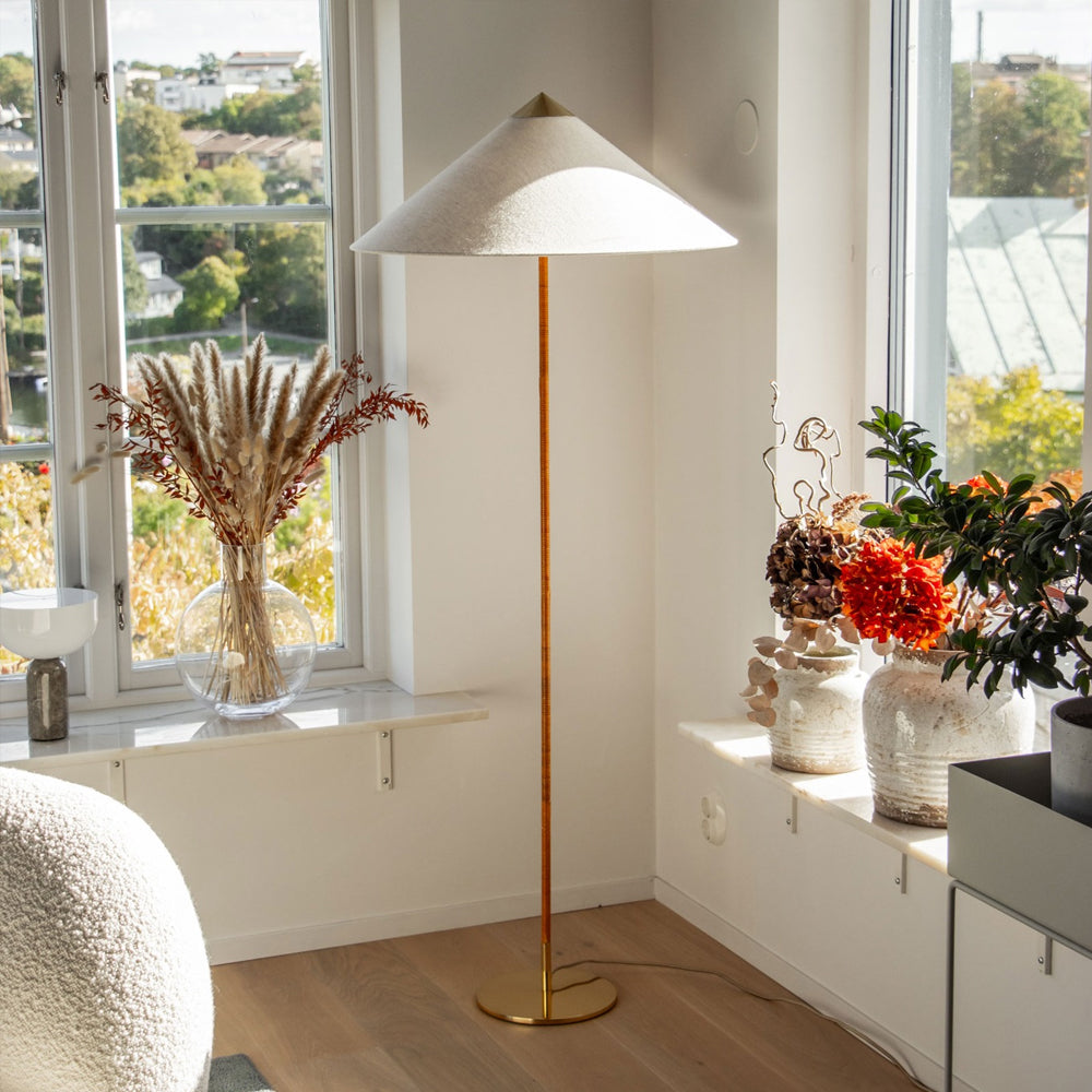 In this photo, a Clérachic floor lamp with a textured white shade by a sunny window, with dried grasses in a glass vase and autumn flowers on the sill.