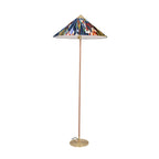 This Clérachic floor lamp with a dark blue floral printed shade, a cane-wrapped stem and a brass base, on a white backdrop.