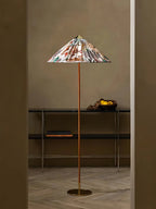 This Clérachic floor lamp with a printed floral shade stands in a doorway above a console with a bowl of fruit, on a pale herringbone floor.