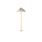 Small Clérachic floor lamp with a printed shade and a brass base on a plain white backdrop, seen from further away.