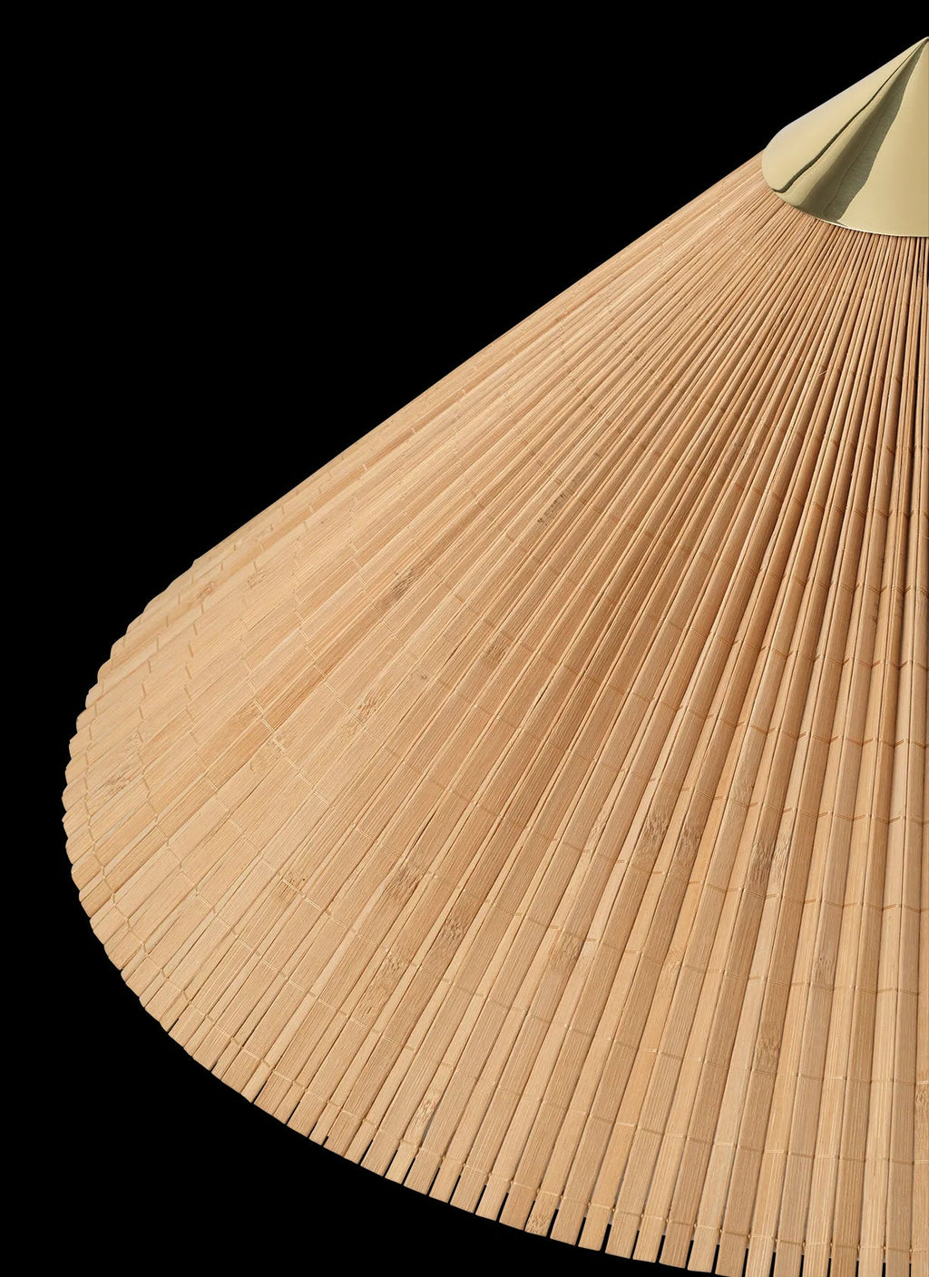 Close view of the fine bamboo slats on the shade of this Clérachic floor lamp, with a brass cap at the top, on a black backdrop.
