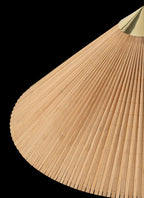 Close view of the fine bamboo slats on the shade of this Clérachic floor lamp, with a brass cap at the top, on a black backdrop.