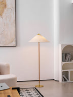 Clérachic floor lamp with a linen-look shade in a white room, beside a cream boucle sofa and a patterned black and white rug.