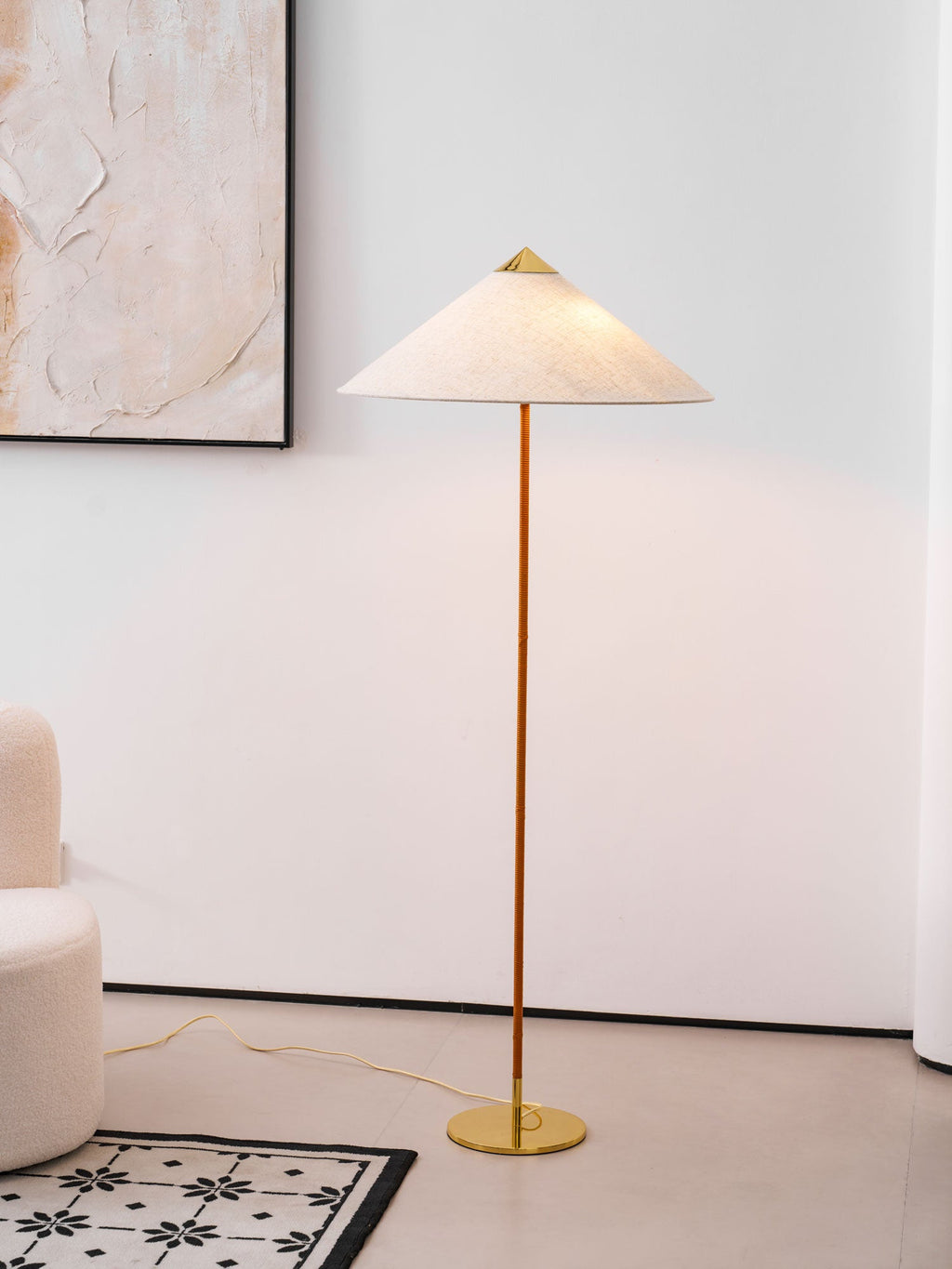 Clérachic floor lamp with a natural linen-look shade beside an abstract painting, with a white boucle sofa and a low shelf.