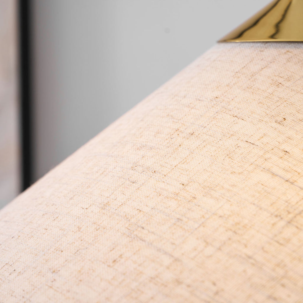 Close view of the slubbed natural linen-look weave of this Clérachic floor lamp shade, with a polished brass cap at the top edge.