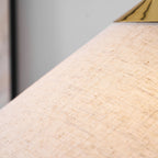 Close view of the slubbed natural linen-look weave of this Clérachic floor lamp shade, with a polished brass cap at the top edge.