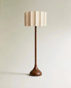 Clérachic floor lamp in full view, a tall wooden stem flowing into a rounded base beneath a pleated, hand-stitched fabric shade.