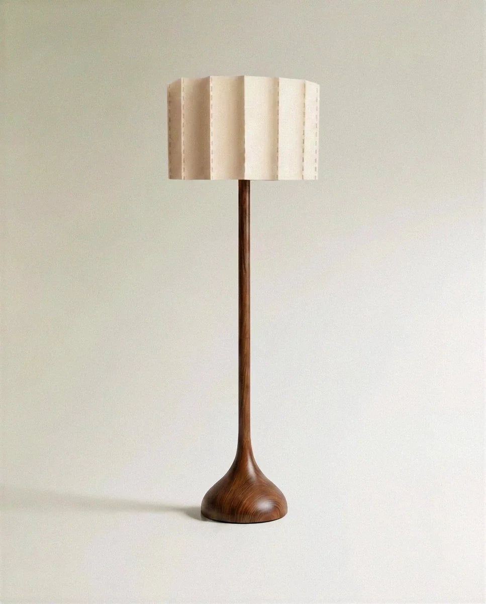 Clérachic floor lamp in full view, a tall wooden stem flowing into a rounded base beneath a pleated, hand-stitched fabric shade.