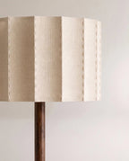 Close view of the Clérachic floor lamp's pleated cream fabric shade, with visible stitching along each fold above the wooden stem.