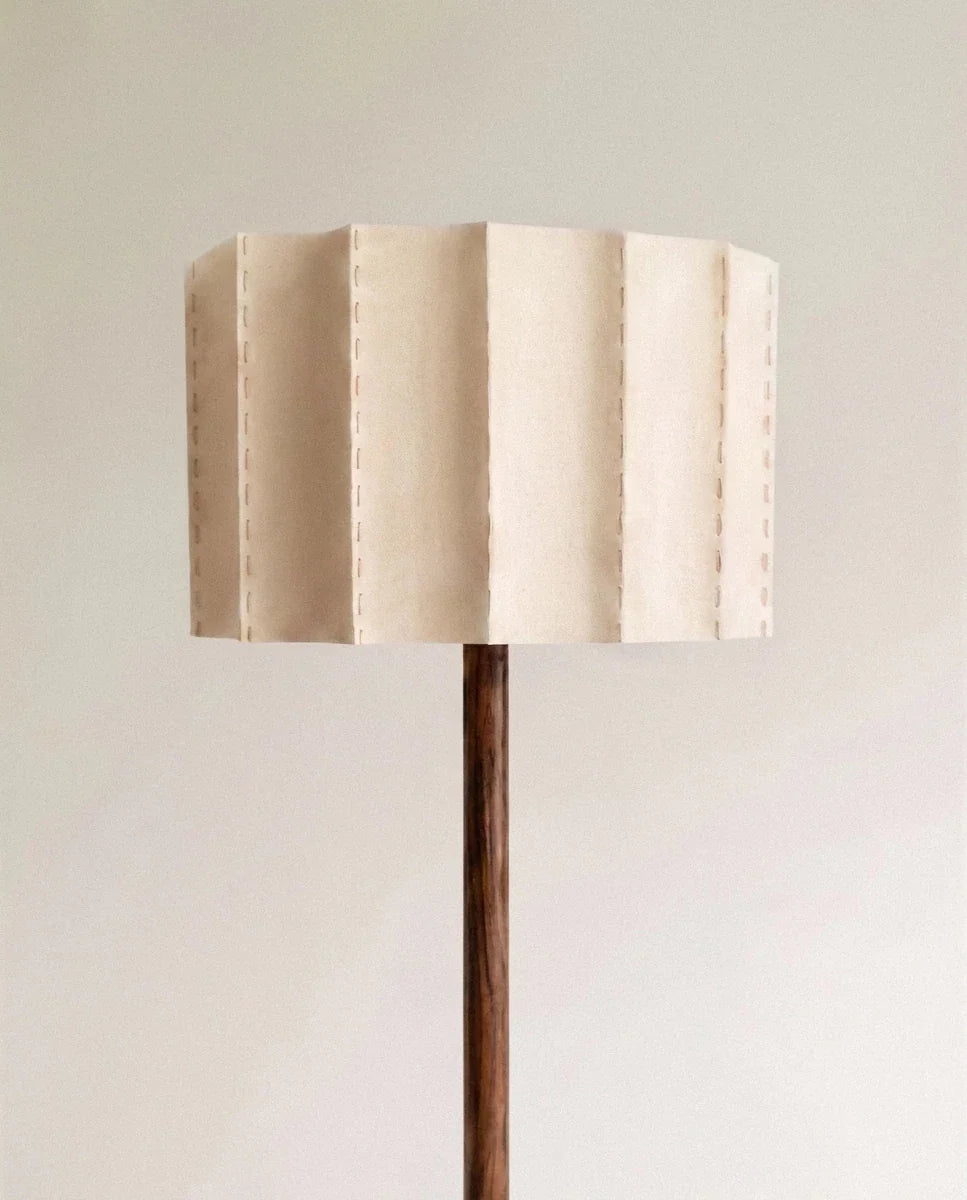 Clérachic floor lamp shade in natural fabric with dashed stitching along every pleat, set on a slim dark wooden stem.