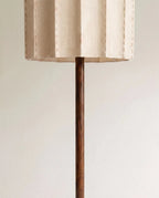 Underside of the Clérachic floor lamp shade showing its pleated fabric edge where the wooden stem meets the shade.