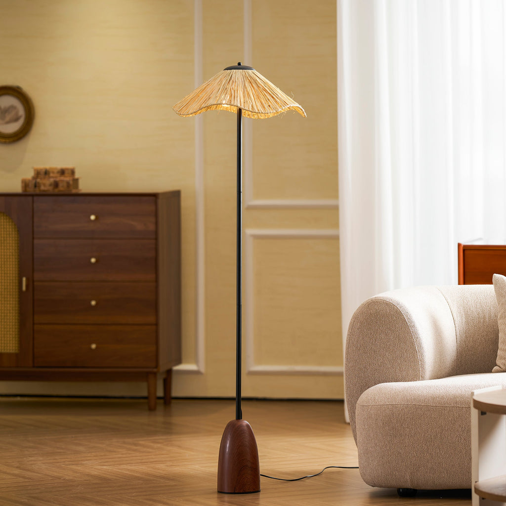 A Clérachic raffia-shade floor lamp stands by a cream boucle sofa and a walnut chest of drawers, with sheer curtains behind.
