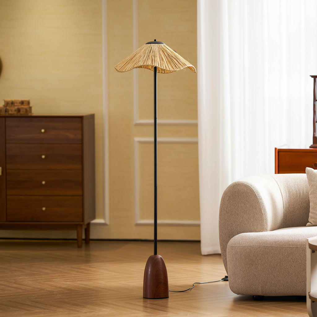 Beside a rounded cream sofa, this Clérachic floor lamp's walnut base and black stem rise to a lit raffia shade.