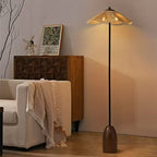 The raffia-shade Clérachic floor lamp stands behind a cream sofa with a fringed throw, in front of a carved wooden sideboard.