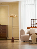 From farther back, a Clérachic raffia-shade floor lamp stands in a bright room with sheer curtains, a cream sofa and a wooden chest.