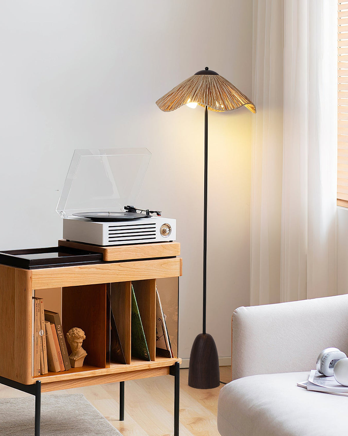 Beside a record player on a wooden shelf, this Clérachic raffia-shade floor lamp stands in a bright room with a cream sofa.